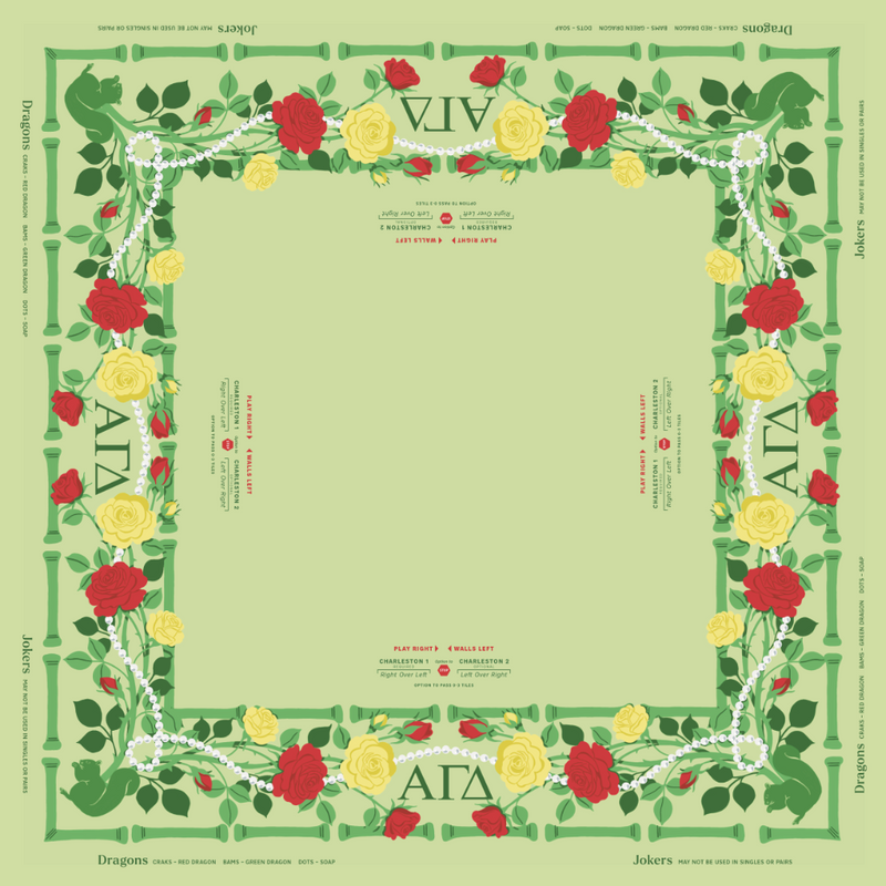 Alpha Gamma Delta MIGTM Mahjong Mat with a pale green center and a floral border. The border features red and yellow roses, green leaves, white vine-like lines, and green geometric corner elements.