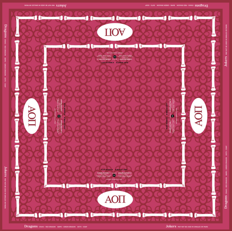 A square jigsaw puzzle cover featuring a symmetrical design with a dark pink background, a white bamboo border, and white oval sections containing the Greek letters Alpha and Omega (ΑΧ). The text 'Dragon's' and 'Jokers' is visible at the bottom, and 'Puzzle' is printed on the sides.
